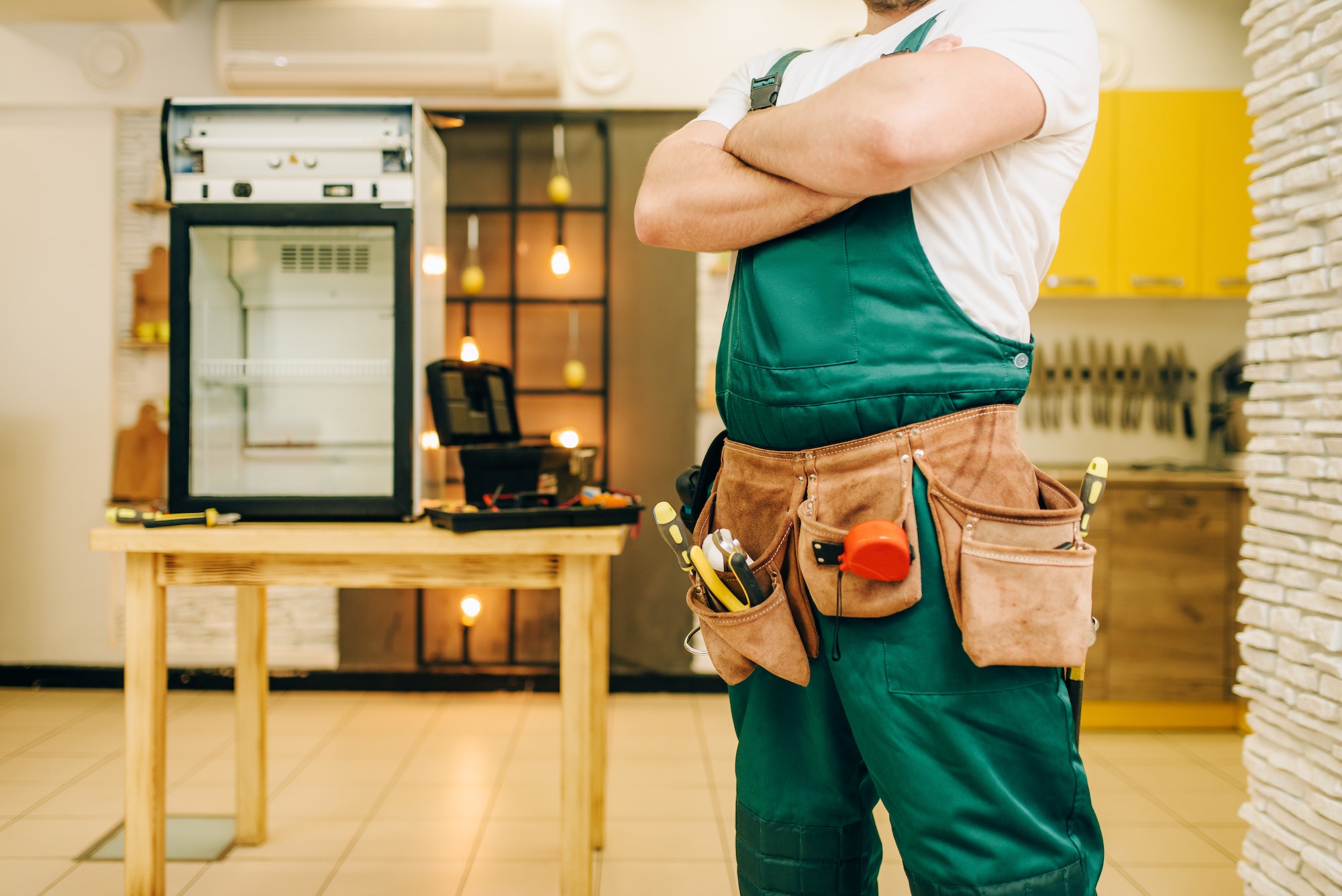 Worker in uniform against refrigerator on table